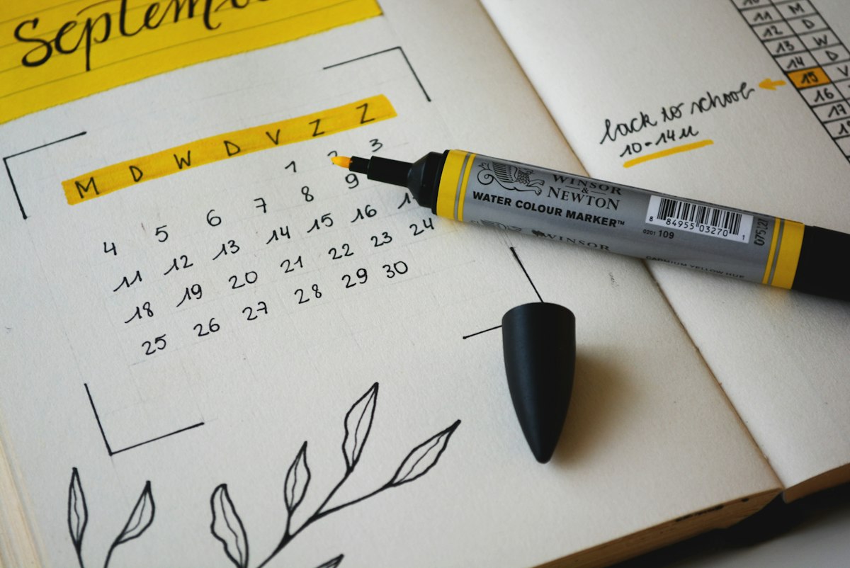 Hands marking dates on a wall calendar for monthly planning
