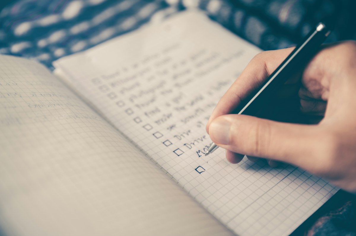 Desk with paper planner open beside a laptop, suggesting weekly time allocation review